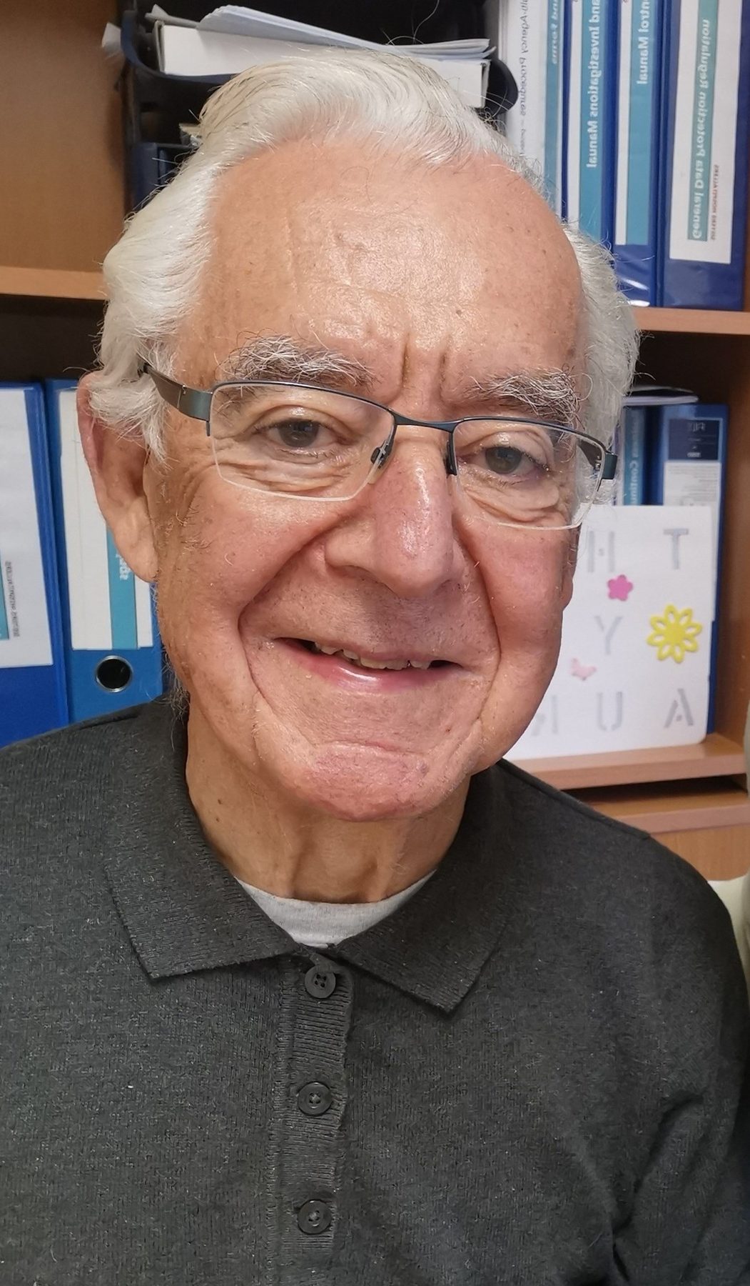 Brian Hamill in later life, smiling in front of a bookshelf